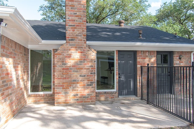 822 Red Rock Canyon Dr, Katy, TX 77450 - entrance to property featuring roof with shingles, brick siding, a chimney, and a patio area