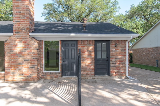 822 Red Rock Canyon Dr, Katy, TX 77450 - view of exterior entry with brick siding, a chimney, and roof with shingles