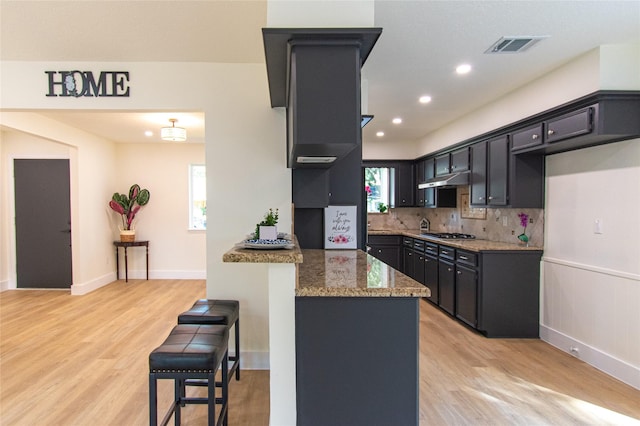 822 Red Rock Canyon Dr, Katy, TX 77450 - kitchen featuring stone counters, a kitchen bar, stainless steel gas cooktop, a peninsula, and light wood finished floors