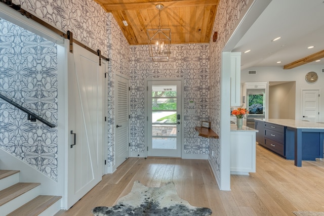 204 Blue Waters Dr, Horseshoe Bay, TX 78657 - foyer entrance with wallpapered walls, a barn door, light wood finished floors, stairs, and vaulted ceiling