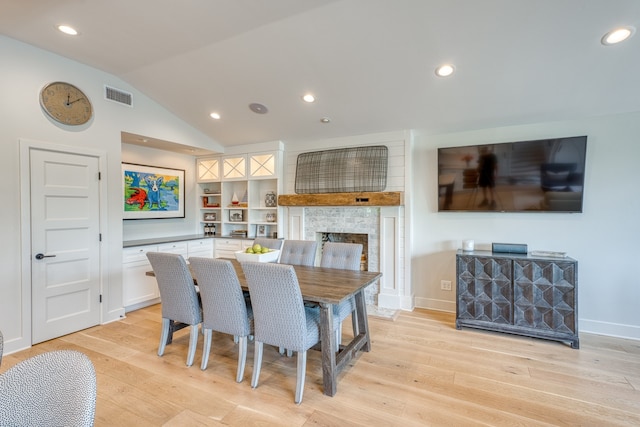 204 Blue Waters Dr, Horseshoe Bay, TX 78657 - dining room with a large fireplace, light wood-style flooring, lofted ceiling, recessed lighting, and baseboards