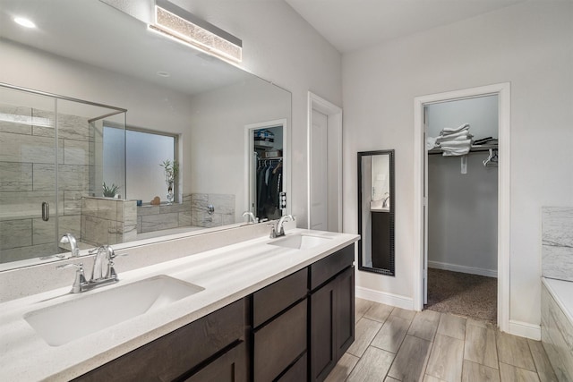 2715 Wembley Way, Rosenberg, TX 77471 - bathroom with a spacious closet, double vanity, a stall shower, a tub, and wood finish floors