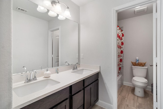 2715 Wembley Way, Rosenberg, TX 77471 - bathroom with double vanity, toilet, wood finished floors, and shower / bathtub combination with curtain