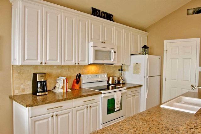 13015 Gulf Beach Dr, Freeport, TX 77541 - kitchen featuring white appliances, vaulted ceiling, tasteful backsplash, a sink, and white cabinetry