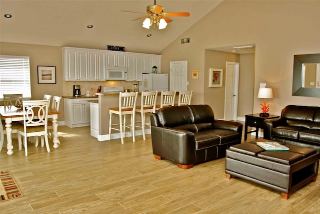13015 Gulf Beach Dr, Freeport, TX 77541 - living area with ceiling fan, light wood-style floors, high vaulted ceiling, and baseboards