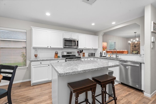 21343 Slate Crossing Ln, Katy, TX 77449 - kitchen with appliances with stainless steel finishes, a sink, light wood-type flooring, a breakfast bar area, and a chandelier