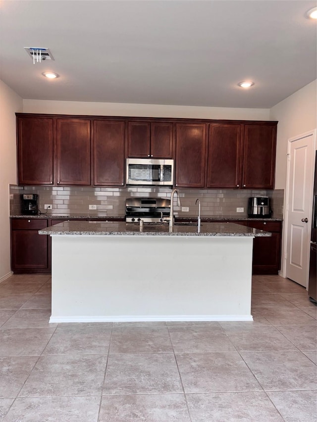 5130 Klein Orchard Dr, Houston, TX 77066 - kitchen featuring stainless steel appliances, dark stone counters, tasteful backsplash, a kitchen island with sink, and recessed lighting