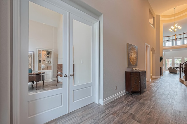27923 Coulter Dr, Spring, TX 77386 - hallway featuring dark wood finished floors, a high ceiling, a chandelier, and arched walkways
