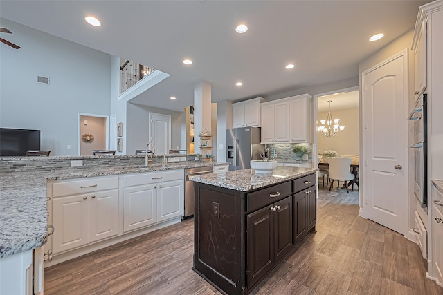 27923 Coulter Dr, Spring, TX 77386 - kitchen featuring appliances with stainless steel finishes, white cabinets, light wood-style flooring, a chandelier, and recessed lighting