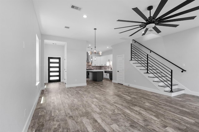 6613 Ave O, Houston, TX 77011 - unfurnished living room with a chandelier, stairway, wood finished floors, recessed lighting, and a ceiling fan