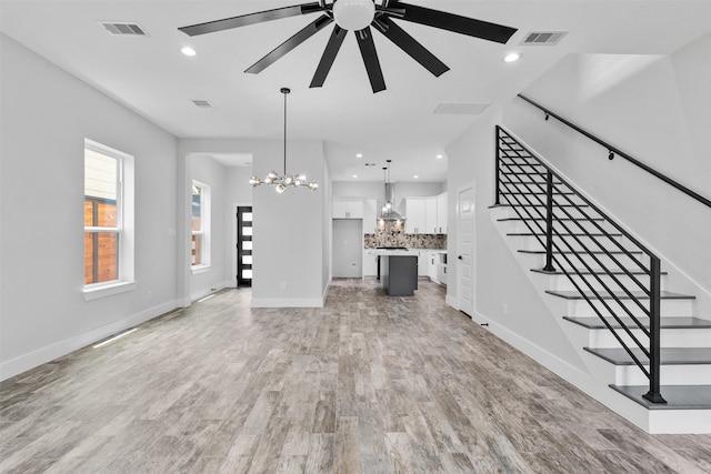 6613 Ave O, Houston, TX 77011 - unfurnished living room featuring a chandelier, a ceiling fan, stairway, light wood-style floors, and recessed lighting