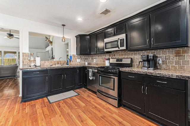 10922 Graywood Ct, La Porte, TX 77571 - kitchen with appliances with stainless steel finishes, dark cabinets, a sink, and light wood-style flooring