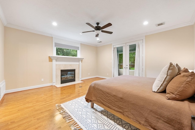 11710 Creek View Ln, Conroe, TX 77385 - bedroom with access to outside, light wood-style flooring, ornamental molding, recessed lighting, and a tile fireplace