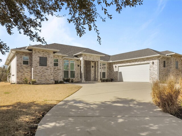 236 Bentwood Dr, Montgomery, TX 77356 - prairie-style house featuring a garage, concrete driveway, brick siding, a front yard, and roof with shingles