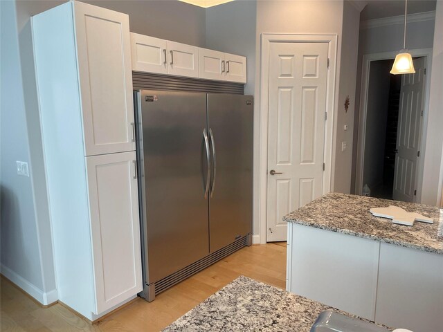 236 Bentwood Dr, Montgomery, TX 77356 - kitchen featuring stainless steel built in fridge, light wood-style flooring, white cabinetry, light stone counters, and ornamental molding