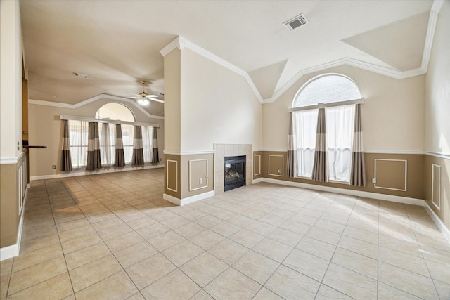 10115 Willow Crossing Dr, Houston, TX 77064 - unfurnished living room featuring light tile patterned floors, vaulted ceiling, a tile fireplace, a ceiling fan, and a wainscoted wall