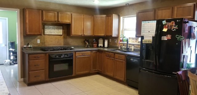 27491 Lantern Ln, New Caney, TX 77357 - kitchen featuring black appliances, dark countertops, light tile patterned floors, and brown cabinets