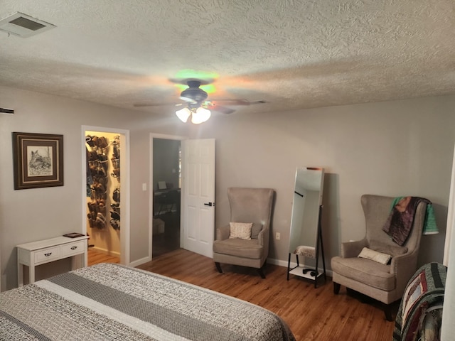 27491 Lantern Ln, New Caney, TX 77357 - bedroom with wood finished floors, a textured ceiling, a walk in closet, a ceiling fan, and a closet