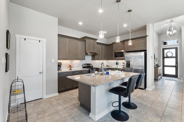 6903 Aspen Peak Dr, Baytown, TX 77521 - kitchen featuring stainless steel appliances, tasteful backsplash, light stone counters, under cabinet range hood, and hanging light fixtures