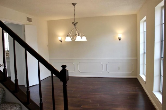 4907 Sabrina Dr, Houston, TX 77066 - unfurnished dining area featuring dark wood finished floors, a chandelier, stairs, a wainscoted wall, and a decorative wall