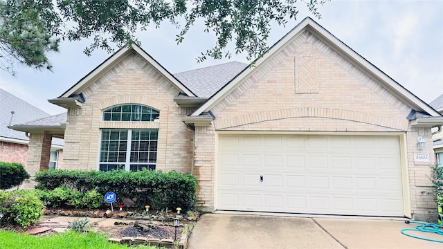 25023 Ivy Trace Ln, Katy, TX 77494 - french country style house featuring a garage, brick siding, concrete driveway, and roof with shingles