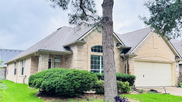 25023 Ivy Trace Ln, Katy, TX 77494 - french provincial home featuring a shingled roof, brick siding, concrete driveway, and a garage