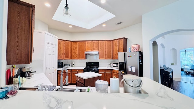 25023 Ivy Trace Ln, Katy, TX 77494 - kitchen featuring stainless steel appliances, arched walkways, under cabinet range hood, brown cabinets, and recessed lighting