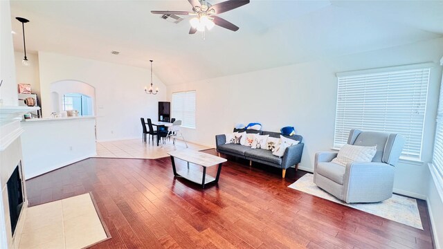 25023 Ivy Trace Ln, Katy, TX 77494 - living room featuring vaulted ceiling, arched walkways, a fireplace with flush hearth, wood finished floors, and a ceiling fan