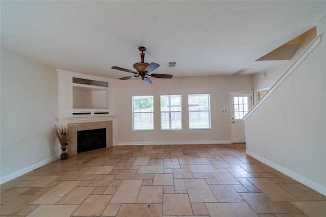19422 Harvest Stream Way, Houston, TX 77084 - unfurnished living room featuring a ceiling fan, healthy amount of natural light, stone tile flooring, and a tiled fireplace