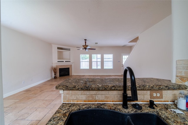 19422 Harvest Stream Way, Houston, TX 77084 - kitchen with a sink, a ceiling fan, a fireplace, baseboards, and stone tile flooring