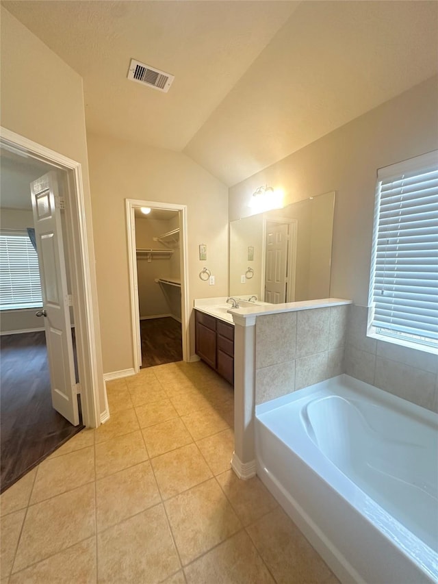 8239 Polaris Point Ln, Cypress, TX 77433 - bathroom with a garden tub, vanity, tile patterned floors, vaulted ceiling, and a walk in closet