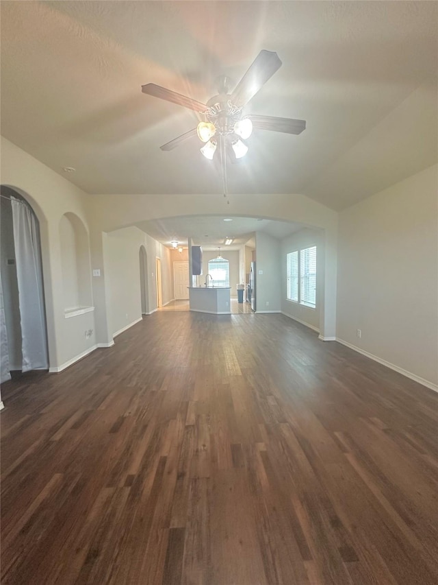 8239 Polaris Point Ln, Cypress, TX 77433 - unfurnished living room featuring dark wood-type flooring, a ceiling fan, arched walkways, and baseboards