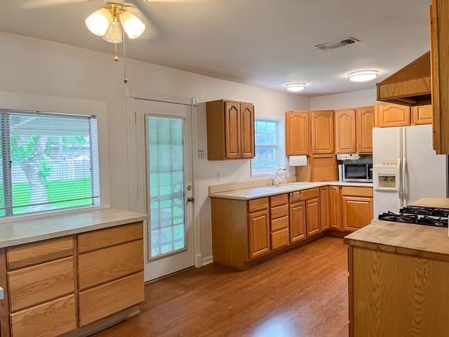 9401 Montgomery Ln, La Porte, TX 77571 - kitchen with white refrigerator with ice dispenser, stainless steel microwave, a ceiling fan, wood finished floors, and a sink