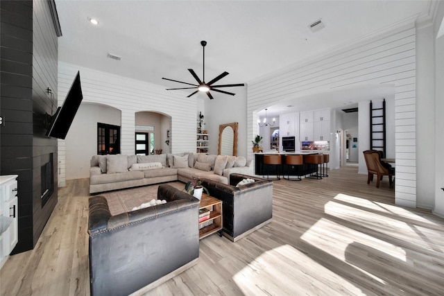 11698 Creek View Ln, Conroe, TX 77385 - living room with arched walkways, light wood-style flooring, ceiling fan, ornamental molding, and a fireplace