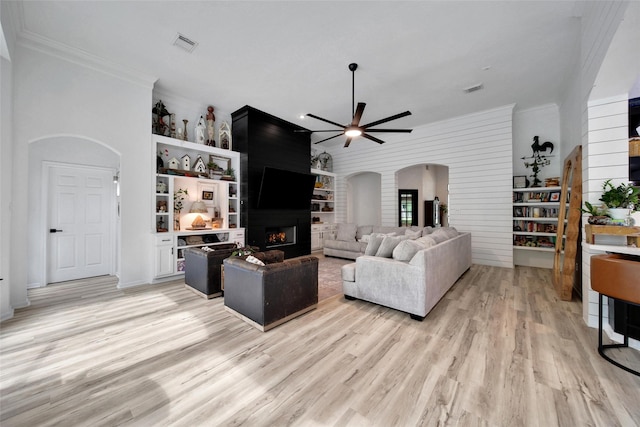 11698 Creek View Ln, Conroe, TX 77385 - living room with arched walkways, a fireplace, ceiling fan, light wood finished floors, and ornamental molding