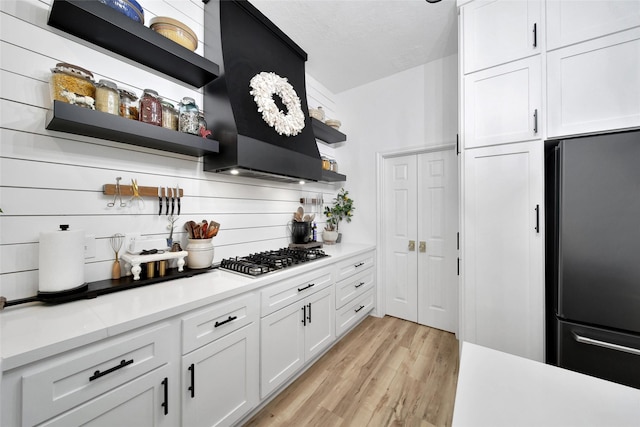 11698 Creek View Ln, Conroe, TX 77385 - kitchen with freestanding refrigerator, open shelves, stainless steel gas cooktop, light wood-style flooring, and white cabinets