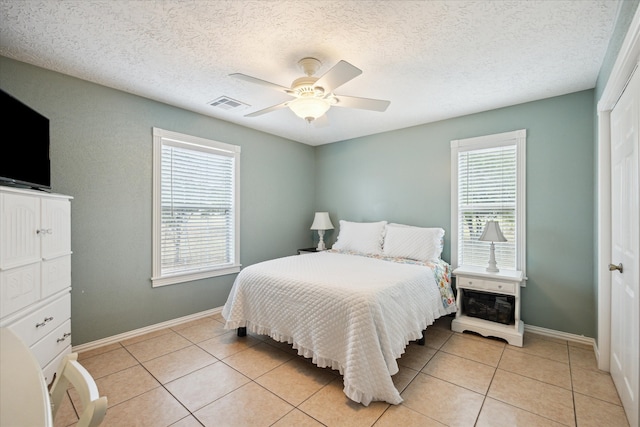 115 N River Place Rd, Rio Frio, TX 78879 - bedroom with light tile patterned floors, baseboards, ceiling fan, and a textured ceiling