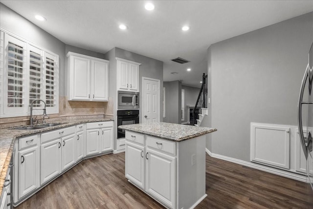 16610 Avenfield Rd, Tomball, TX 77377 - kitchen featuring black oven, stainless steel microwave, dark wood-style flooring, a center island, and white cabinetry