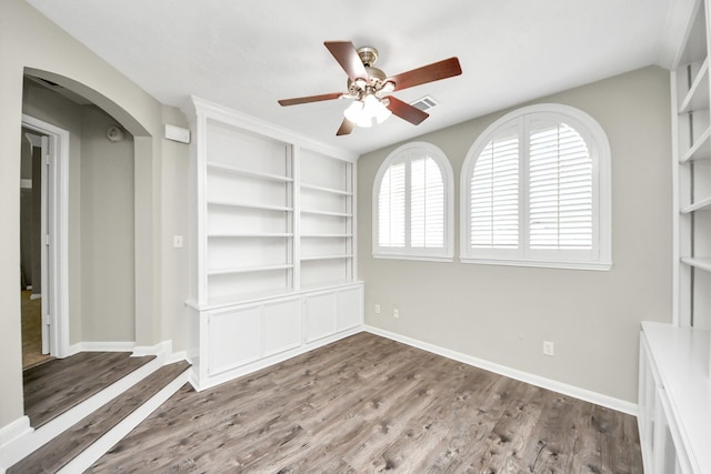 12819 Kingsbridge Ln, Houston, TX 77077 - spare room with a ceiling fan, wood finished floors, baseboards, arched walkways, and built in shelves