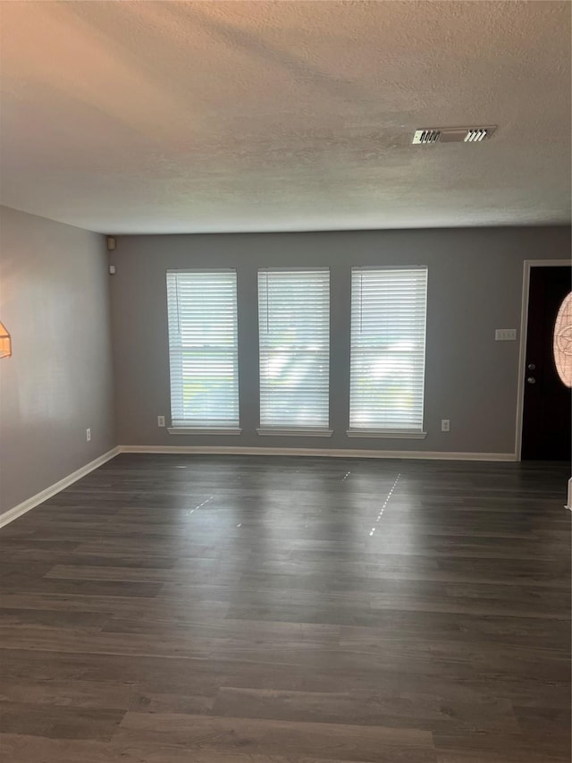 16219 Purpleridge Ct, Houston, TX 77053 - unfurnished living room with baseboards, plenty of natural light, a textured ceiling, and dark wood-type flooring