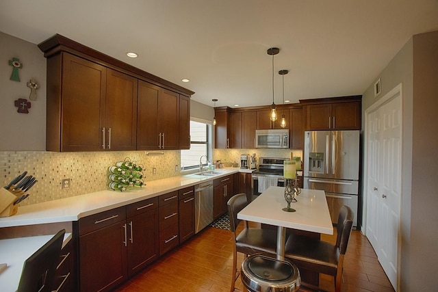 907 Davis Rd, League City, TX 77573 - kitchen with appliances with stainless steel finishes, a sink, decorative backsplash, decorative light fixtures, and dark wood finished floors