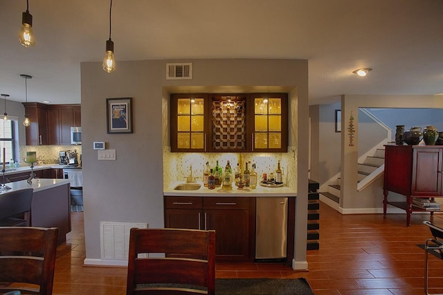 907 Davis Rd, League City, TX 77573 - indoor dry bar with stainless steel microwave, decorative backsplash, stairs, pendant lighting, and dark wood-style flooring