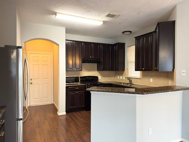 5227 Brinkman Ct, Houston, TX 77091 - kitchen featuring stainless steel appliances, under cabinet range hood, arched walkways, dark wood-type flooring, and a peninsula