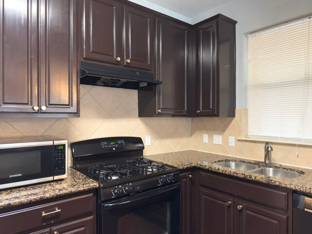 5227 Brinkman Ct, Houston, TX 77091 - kitchen featuring black range with gas stovetop, stainless steel microwave, under cabinet range hood, a sink, and tasteful backsplash