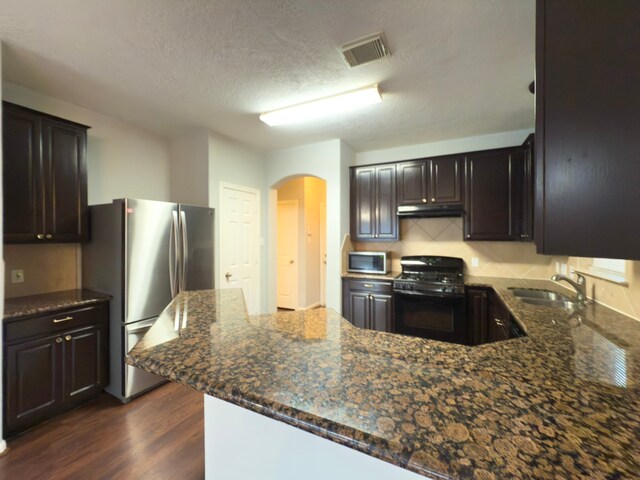 5227 Brinkman Ct, Houston, TX 77091 - kitchen with appliances with stainless steel finishes, a sink, arched walkways, under cabinet range hood, and a peninsula