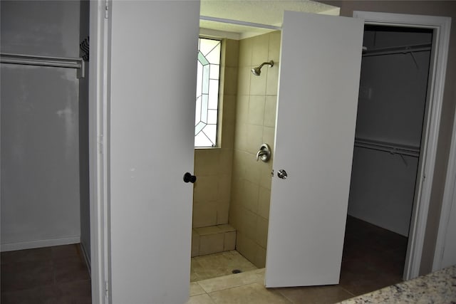 18318 Ella Blvd, Spring, TX 77388 - bathroom with tiled shower, a walk in closet, and tile patterned flooring