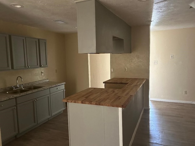6322 Purple Sage Rd, Houston, TX 77049 - kitchen featuring butcher block counters, a sink, a textured ceiling, dark wood-style floors, and baseboards