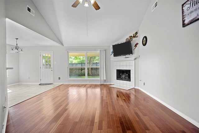 1726 Havelock Dr, Spring, TX 77386 - unfurnished living room featuring hardwood / wood-style floors, a tile fireplace, a ceiling fan, vaulted ceiling, and a chandelier
