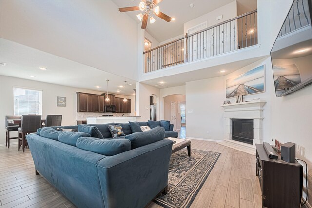 4507 Shallow Hill Ct, Houston, TX 77084 - living area featuring a ceiling fan, light wood-style floors, arched walkways, a glass covered fireplace, and a towering ceiling