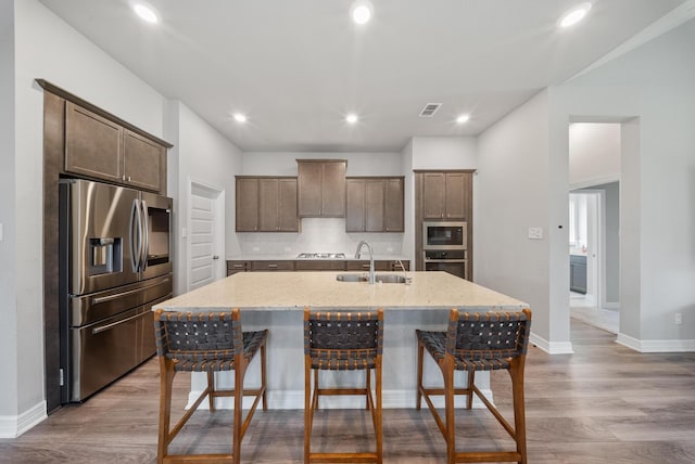 29023 Laurel Grove Ln, Fulshear, TX 77441 - kitchen with stainless steel appliances, a sink, a breakfast bar area, light wood-type flooring, and an island with sink